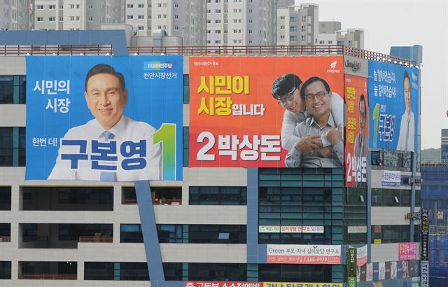 충남 천안시장 선거에 나선 더불어민주당 구본영 후보와 자유한국당 박상돈 후보 선거사무실이 입주한 천안시청 앞 M빌딩 외벽에 현수막이 나란히 걸려있다.