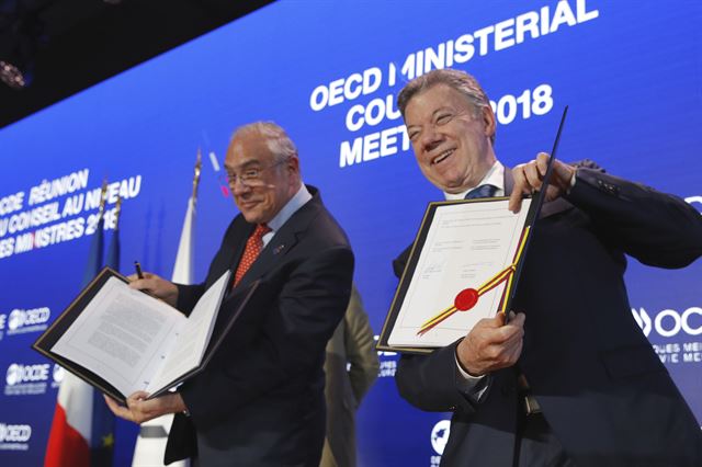 프랑스 파리에서 30일(현지시간) '2018 OECD 각료 이사회'에 참석한 후안 마누엘 산토스 콜롬비아 대통령(오른쪽) 이 앙헬 구리아 OECD 사무총장과 함께 서명을 마친 콜롬비아 OECD 가입 합의문을 들어보이고 있다. 콜롬비아는 중남미 국가로서는 3번째로, OECD 37번째 회원국이 되었다. AP 연합뉴스