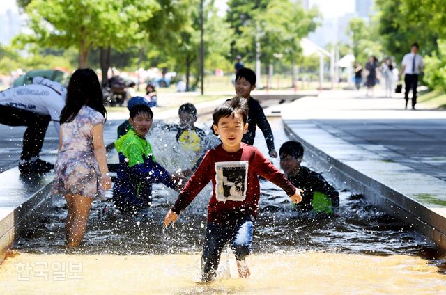 서울 낮 기온이 30도에 이른 1일 서울 여의도 한강공원을 찾은 아이들이 마포대교 아래에서 물놀이하며 더위를 식히고 있다. 김주성 기자