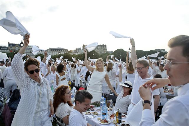 프랑스 파리의 앵발리드에서 3일(현지시간) 올해로 30회를 맞는 '디네 앙 블랑(Diner en Blanc)'이 열리고 있는 가운데 행사에 참여한 시민들이 하얀 냅킨을 흔들고 있다. AP 연합뉴스