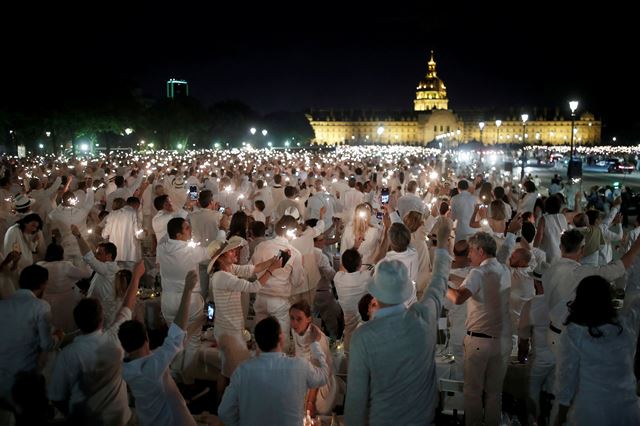 프랑스 파리의 앵발리드 부근에서 3일(현지시간) '디네 앙 블랑(Diner en Blanc)'이 열리고 있는 가운데 행사에 참석한 시민들이 불꽃을 들고 서 있다. 해마다 파리의 다른 장소에서 열리는 '디네 앙 블랑'에서는 머리부터 발끝까지 흰색으로 차려입은 사람들이 야외에 모여 하얀색으로 꾸며진 테이블에 앉아 만찬을 즐긴다. 로이터 연합뉴스