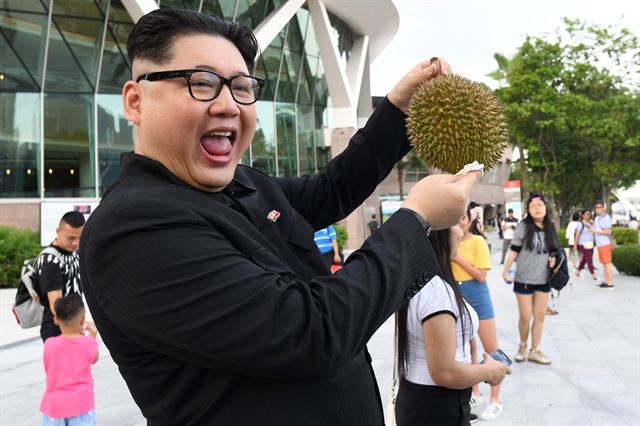 지난 27일 싱가포르의 머리리언 파크에 김정은 북한 국무위원장 분장을 한 호주 국적의 중국인인 하워드씨가 두리안을 들고 포즈를 취하고 있다. AFP연합뉴스