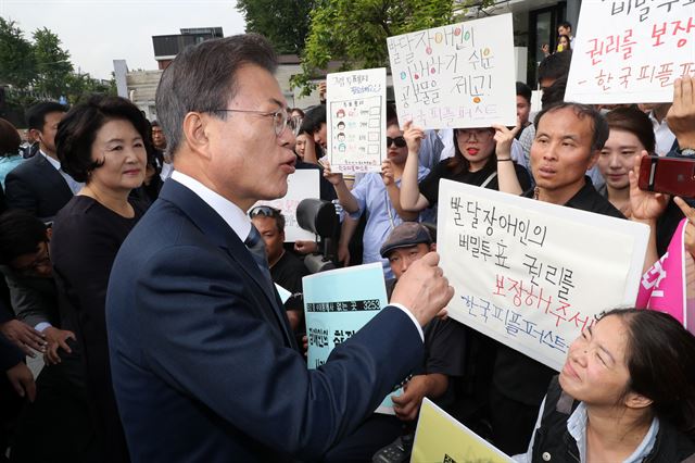 문재인 대통령과 김정숙 여사가 8일 오전 서울 종로구 청와대 인근 한 투표소에서 6·13 지방선거 및 국회의원 재보궐선거 사전투표를 마치고 장애인 참정권을 요구하는 장애인단체 회원들과 대화를 하고 있다. 한국일보