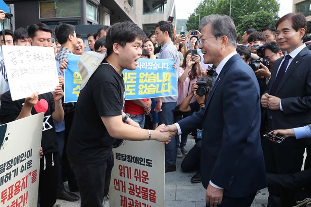 문재인 대통령이 8일 서울 종로구 삼청동주민센터에서 사전 투표를 한뒤 참정권 보장시위를 하는 장애인단체와 만나고 있다. 한국일보