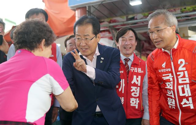 6·13 지방선거를 앞둔 마지막 주말인 9일 홍준표 자유한국당 대표가 해운대구 반송골목시장에서 이 지역 국회의원 보궐선거에 출마한 김대식 후보, 지방선거 후보들과 함께 주민들과 인사하고 있다. 연합뉴스