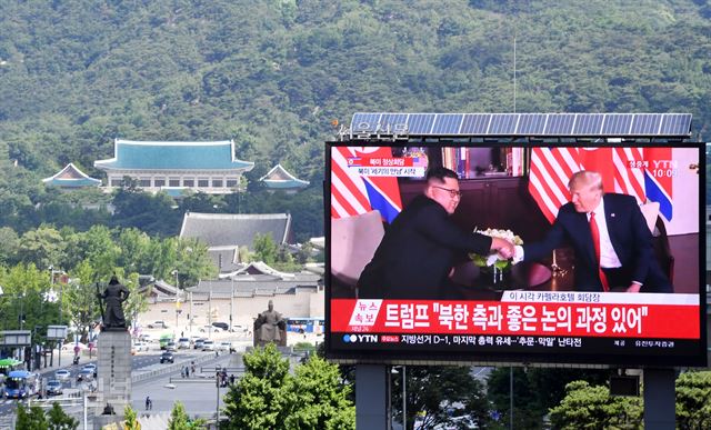 12일 오전 트럼프 미국 대통령과 김정은 북한 국무위원장이 정상회담장에서 악수하는 장면이 청와대가 보이는 서울 광화문의 뉴스 전광판에 중계되고 있다. 신상순 선임기자