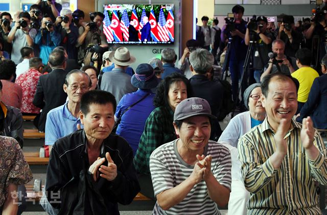 서울] 12일 서울역 대합실에서 북미 정상회담을 시청하던 시민들이 양 정상이 만나 악수하는 모습을 보며 손뼉을 치고 있다. 고영권 기자