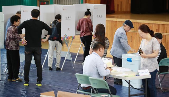 6.13 전국동시 지방선거가 실시된 13일 오전 서울 용산구 이태원초등학교 교육문화관에 마련된 투표소에서 유권자들이 선거인명부를 확인한 뒤 투표하고 있다. 연합뉴스