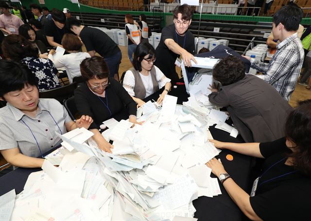 제7회 전국동시지방선거 및 국회의원 재ㆍ보궐선거 사전투표가 끝난 13일 오후 서울 송파구 잠실실내체육관에 마련된 광진구개표소에서 개표사무원들이 개표함에서 표를 꺼내고 있다. 연합뉴스