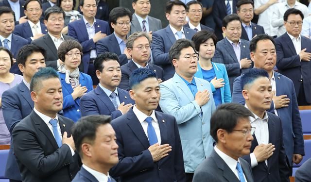 14일 더불어민주당 의원총회에서 짧고 파란색으로 머리를 염색한 의원들이 국기에 경례하고 있다. 연합뉴스