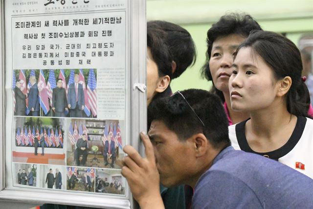 13일 북한 평양에서 시민들이 지하철역 게시판에 게재된 북미 정상회담 관련 내용을 보도한 노동신문을 유심히 살펴보고 있다. 평양=AP·뉴시스