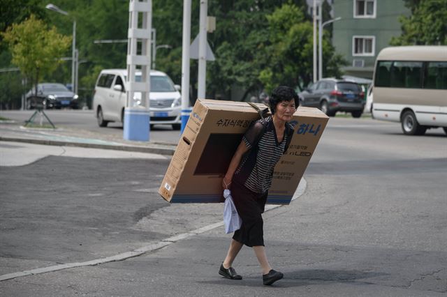 17일 평양 거리에서 한 여성이 LED 텔레비전을 등에 짊어진 채 걷고 있다. 평양=AFP 연합뉴스