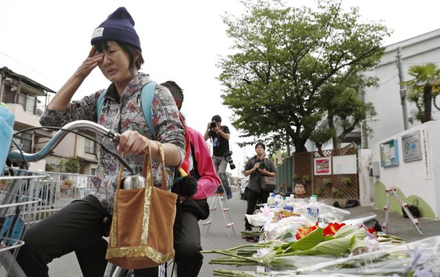 일본 오사카에서 규모 6.1의 지진이 발생한지 하루가 지난 19일(현지시간) 오사카의 타카츠키에서 자전거를 타고 가던 한 여성이 지진 당시 담장이 붕괴되어 9세 소녀가 사망한 사고 현장을 지나가며 눈물을 흘리고 있다. 교도뉴스, AP 연합뉴스