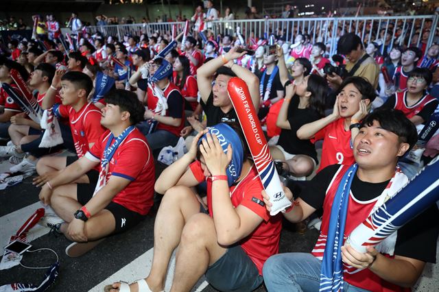 축구 팬들이 18일 서울 강남구 영동대로에서 한국이 득점 기회를 살리지 못하자 아쉬워하고 있다. 연합뉴스