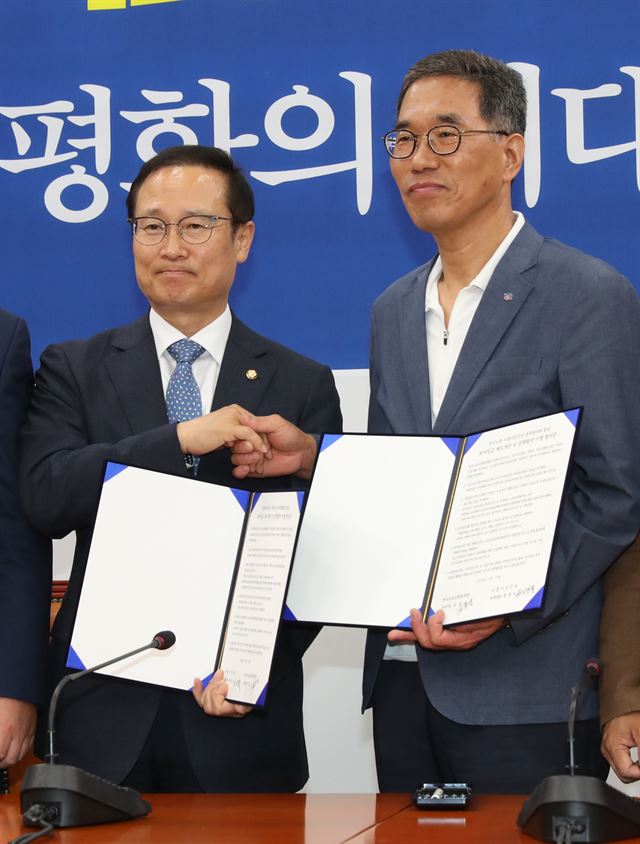 27일 오후 국회에서 열린 더불어민주당-한국노총 정책협의체 고위협의회에서 홍영표(왼쪽) 원내대표와 김주영 위원장이 '최저임금 제도개선 및 정책협약 이행 합의문'을 들고 손을 맞잡고 있다. 연합뉴스.