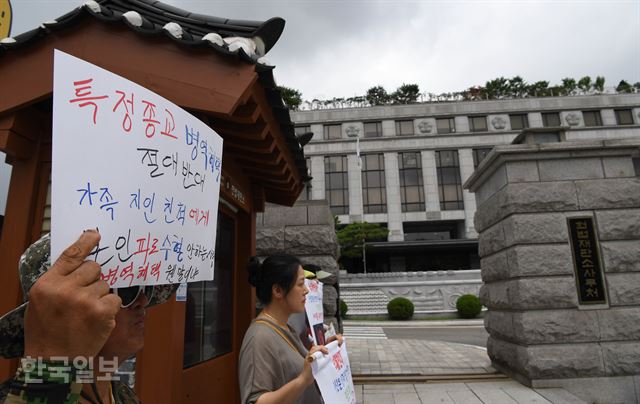 28일 서울 종로구 헌법재판소 대심판정에서 열린 양심적 병역 거부 허용 여부 판결을 앞두고 특정 종교 병역 혜택을 반대하는 시민단체 회원이 종이 피켓을 들고 헌재 앞에서 시위를 벌이고 있다. 신상순 선임기자