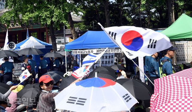 4일 오전 서울 중구 대한문 앞에서 고(故) 쌍용자동차 해고 노동자 고(故) 김모씨를 추모하기 위해 분향소가 설치된 가운데 보수단체 회원들이 태극기를 흔들며 분향소 철수를 요구하고 있다. 고영권 기자