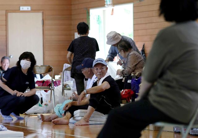 일본 서남부 지역에 1000mm가 넘는 기록적인 폭우가 내려 인명 및 재산 피해가 속출하고 있는 가운데 9일(현지시간) 오카야마 현 구라시키의 마비마을 주민들이 임시 대피소에 모여 앉아 있다. EPA 연합뉴스