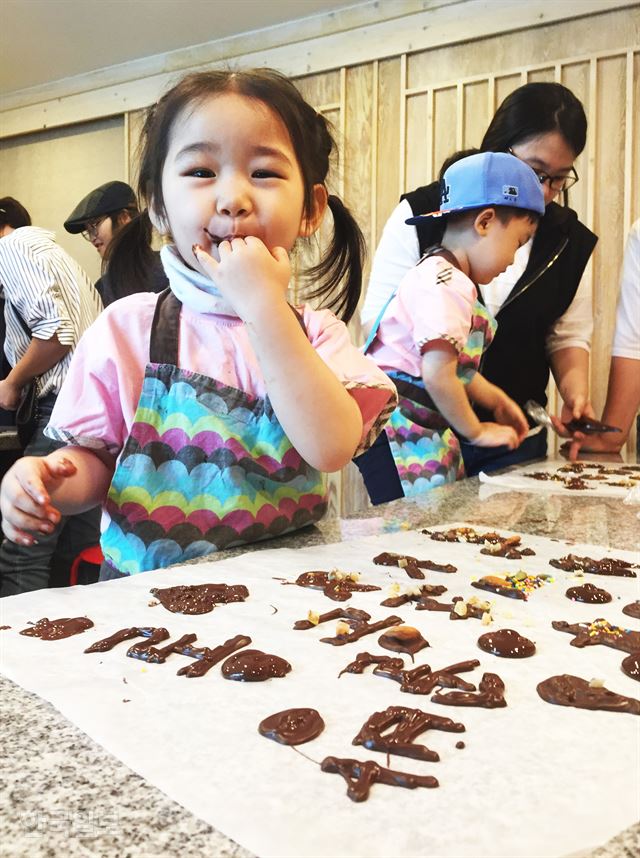 참을 수 없는 유혹, 초콜릿을 만들던 아이가 손에 묻은 초콜릿을 맛보고 있다.