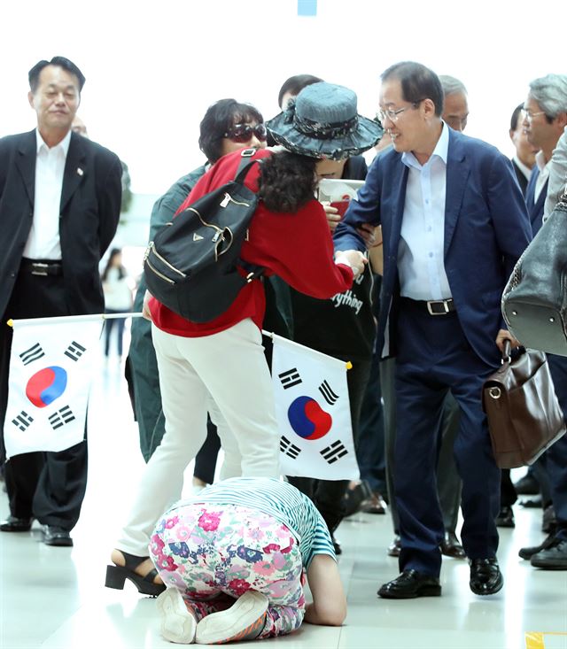 홍준표 자유한국당 전 대표가 미국에서 휴식을 위해 11일 인천공항으로 들어서자 한 지지자가 큰절을 하고 있다. 연합뉴스