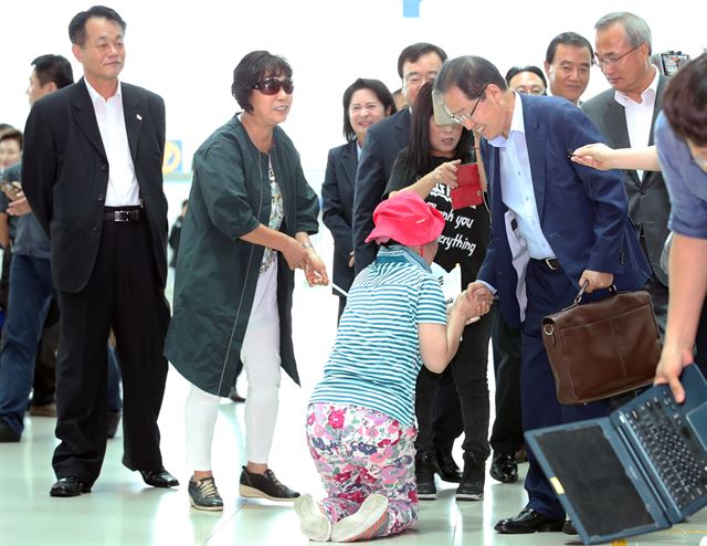 홍준표 자유한국당 전 대표가 휴식을 위해 11일 미국으로 출국하기 위해 인천공항으로 들어서자 한 지지자가 무릎을 꿇고 악수하고 있다. 연합뉴스