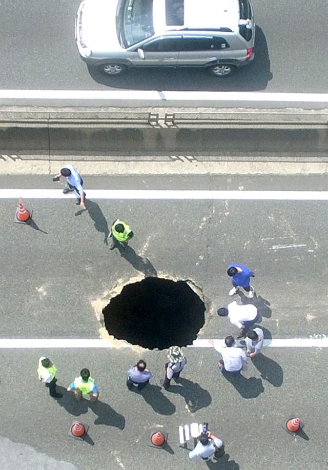 11일 낮 12시 30분께 부산 도시고속도로 번영로 원동에서 서울 방향 200ｍ 지점에 가로 2ｍ, 세로 1ｍ, 깊이 5ｍ가량의 싱크홀이 발생해 복구 작업이 진행되고 있다. 독자 이성복씨 촬영 제공=연합뉴스