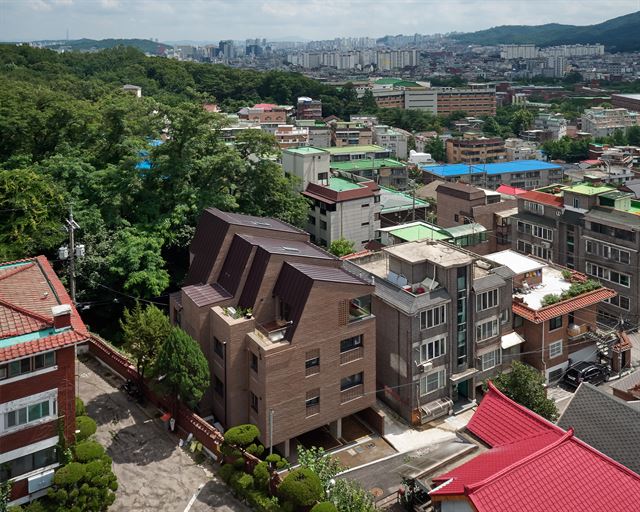 오래된 주택이 밀집한 서울 쌍문동 경사지 막다른 골목에 지어진 닮담집. 인근 우이동에서 6대째 마트를 운영하는 건축주 부부가 11년의 빌라 생활을 청산하고 지은 다가구 주택이다. 노경 건축사진작가