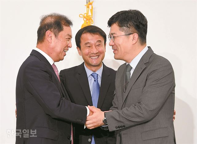 김병준(왼쪽) 자유한국당 비상대책위원장이 19일 국회에서 김 위원장 취임 인사차 방문한 한병도(가운데) 청와대 정무수석으로부터 ‘대통령 문재인’이라고 적힌 축하 난을 전달받은 뒤 송인배 청와대 정무비서관과 악수하고 있다. 오대근 기자