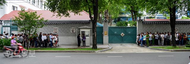 25일 오전 한국행 비자를 받기 위해 호찌민 총영사관 앞에 줄을 선 베트남 사람들. 오전 7시에 문을 열지만 6시 반부터 몰려들기 시작한 사람들이 공안 초소 양쪽으로 길게 늘어서 있다. 이들은 오전 7시부터 차례로 한 사람씩 초소에서 신분 확인을 거친(사진 가운데 부분) 뒤 총영사관 민원실로 들어가며, 민원실 내 번호표를 받은 뒤 비자 신청서를 제출한다. 초청 비자의 경우 이날 번호표를 뽑으면 20~25일 뒤에야 신청서를 접수할 수 있다고 한다. 문제가 없을 경우 신청 접수 뒤 10일 가량 뒤 비자를 받을 수 있다.