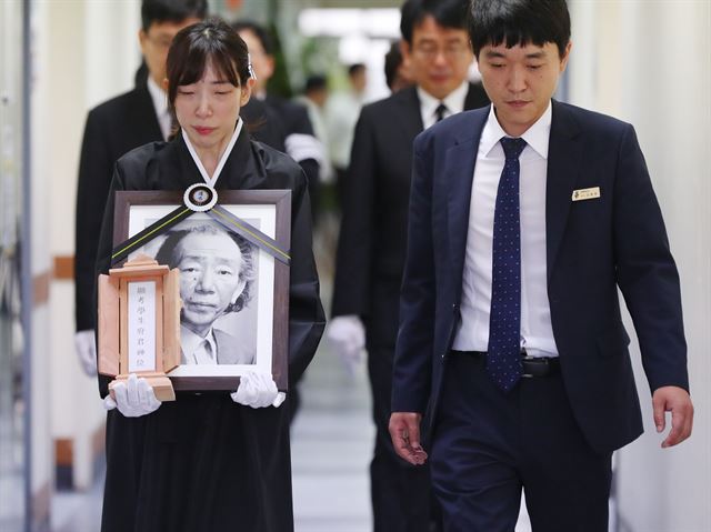 고 최인훈 작가의 딸 윤경씨가 25일 서울대병원 장례식장에서 열린 영결식을 마치고 영정을 옮기고 있다. 연합뉴스