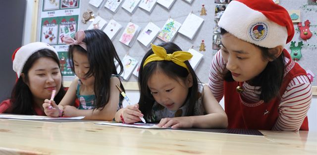 28일 강원 화천군에 문을 연 산타우체국 한국 본점을 찾은 쌍둥이 자매가 핀란드 로바니에미시 산타마을에 보낼 그림엽서를 만들고 있다.