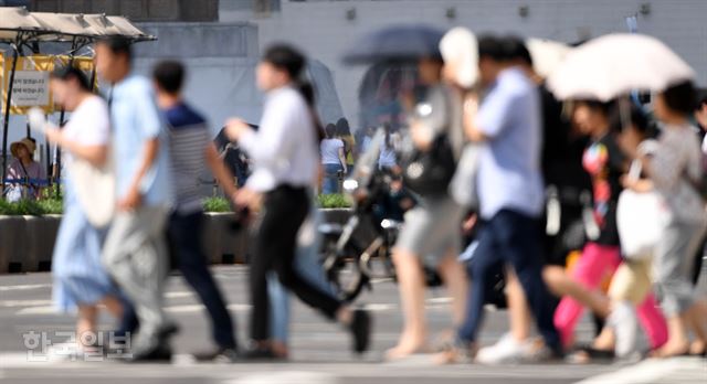 30일 오후 서울 낮 최고기온이 37도까지 오르는 등 기록적인 폭염이 이어지고 있는 가운데 세종로 사거리를 지나는 시민들이 양산 등으로 햇빛을 가린 채 걷고 있다. 서재훈 기자 spring@hankookilbo.com