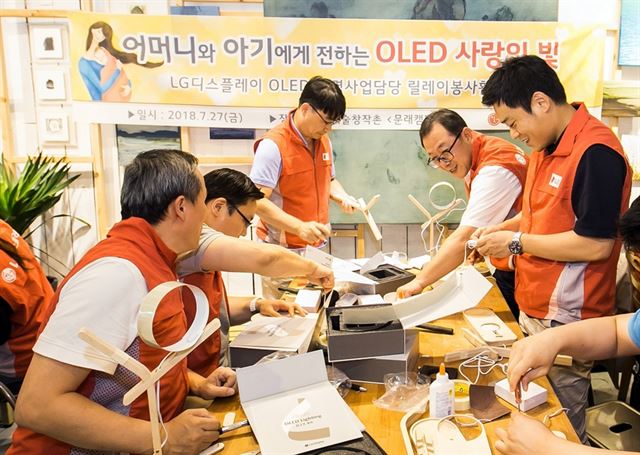 LG디스플레이 OLED조명사업담당 박성수(오른쪽에서 두 번째) 상무를 비롯한 임직원들이 미혼모를 위한 OLED 수유등을 만들고 있다. LG디스플레이 제공