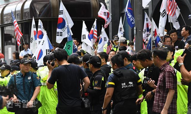 김경수 경남도지사가 드루킹의 댓글조작 행위를 공모한 혐의로 6일 오전 서울 강남구 특검에 출석하자 보수단체 회원들이 태극기를 흔들고 있다. 서재훈 기자