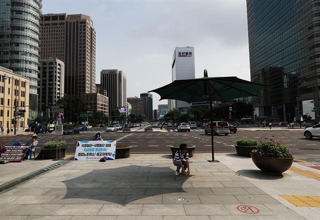 폭염이 이어진 6일 서울 광화문광장에 한 시민이 뜨거운 태양을 피하고 있다. 연합뉴스