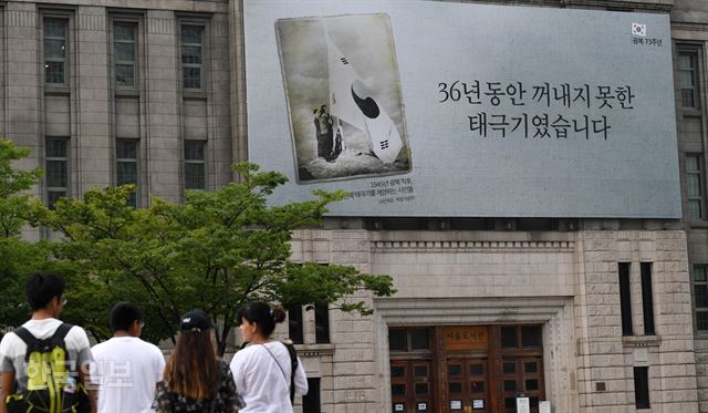 13일 서울광장 꿈새김판에 광복절 기념 현수막이 걸려 있다. '36년 동안 꺼내지 못한 태극기였습니다'라는 문구와 함께 광복 직후 남산에서 대형 태극기를 게양하는 시민들의 모습을 찍은 사진과 설명문이다. 서재훈 기자