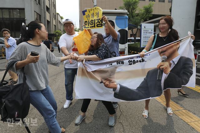 성폭행 등의 혐의로 기소됐던 안희정 전 지사가 1심에서 무죄를 선고받은 14일 서울 마포구 서부지법 앞에서 한 여성이 안희정 전 지사를 지지하는 사람들의 플래카드를 뺏으려 하고 있다. 류효진 기자