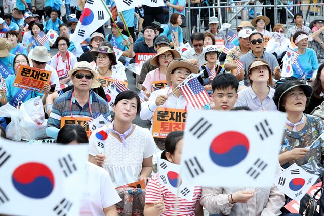 15일 오전 서울 종로구 광화문 광장 인근에서 열린 '건국 70주년 기념식 및 8.15 국가해체세력 규탄 범국민대회'에서 참가자들이 성조기와 태극기를 들고 ‘문재인 대통령 퇴진’ 구호를 외치고 있다 . 뉴시스