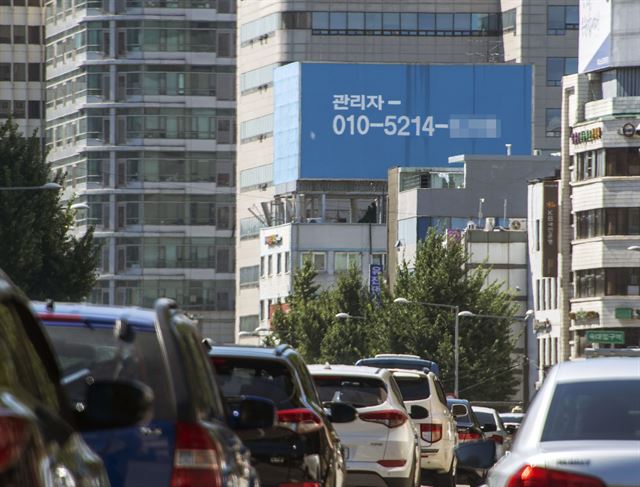 17일 교통 체증을 빚고 있는 서울 한강로 변 건물 옥상에 대형 광고판에 안내 전화 번호가 쓰여 있다.