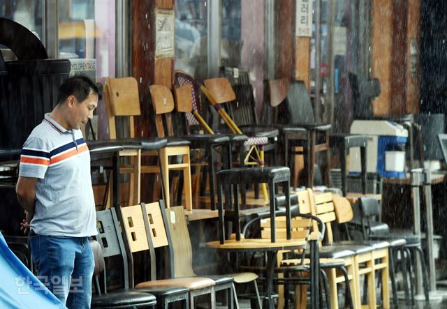 24일 오후 서울 중구 황학시장에 비가 내리는 가운데 중고가구를 판매하는 한 점포에서 주인이 손님을 기다리고 있다. youngkoh@hankookilbo.com