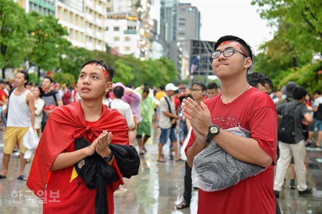 29일 아시안게임 남자축구 한국-베트남 준결승전을 호찌민시 응우옌 후에 광장에 마련된 대형 스크린으로 지켜보며 응원하던 시민들이 자국 팀이 패하자 침통한 표정으로, 하지만 선수들에게 박수를 보내며 일어서고 있다. 호찌민=정민승 특파원