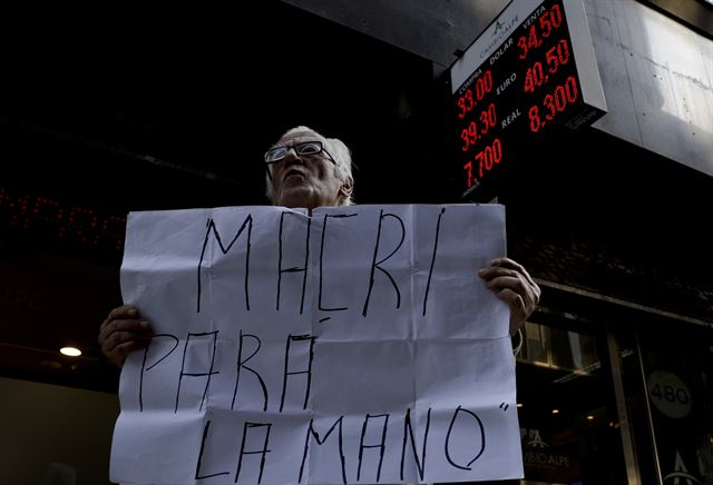 29일 부에노스아이레스의 환전소 앞에서 “Stop Macri”라고 적힌 피켓을 들고 정부의 무능한 경제정책에 항의하고 있다. 이날 아르헨티나의 화폐인 페소화는 사상 최저치를 기록했고, IMF는 마우리시오 마크리 대통령의 요청을 받아 구제금융을 조기 집행키로 했다. 부에노스아이레스=AP 연합뉴스