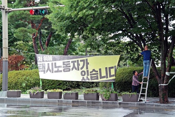 단 하루도 버티기 어려운 한뎃잠을 김씨가 1년씩 견디는 동안, 사람들은 그의 존재를 잊어간다. 김씨의 동료들이 전주시청 앞 인도에 "저 위에 택시 노동자가 있다"는 현수막을 걸고 있다. 전주=김혜영기자