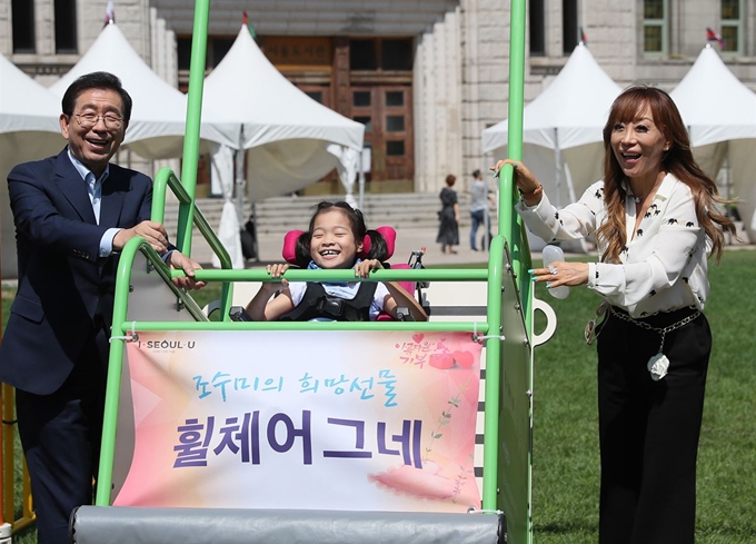 소프라노 조수미(맨 오른쪽)씨와 박원순 서울시장이 31일 서울광장에서 ‘휠체어 그네’를 탄 아이를 밀어주고 있다. 연합뉴스