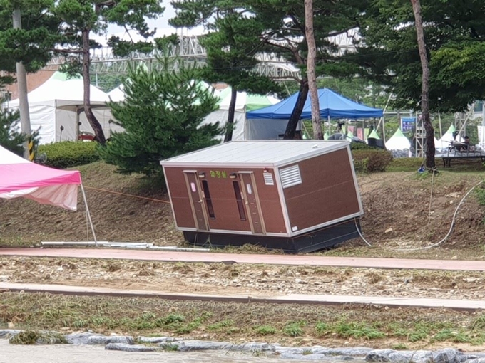 괴산고추축제장에 설치됐던 간이화장실 용 컨테이너가 불어난 급류에 떠내려가 하천 변에 걸터앉아 있다. 한덕동 기자