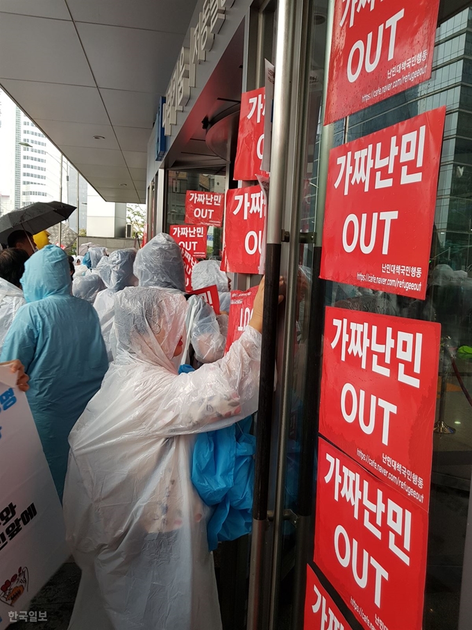 [저작권 한국일보] 서울 중구에 위치한 국가인권위원회 입구에서 제6차 난민반대 집회에 참여한 시민들이 '가짜난민 OUT'이라 적힌 피켓을 건물 입구에 붙이고 있다. 오세훈 기자