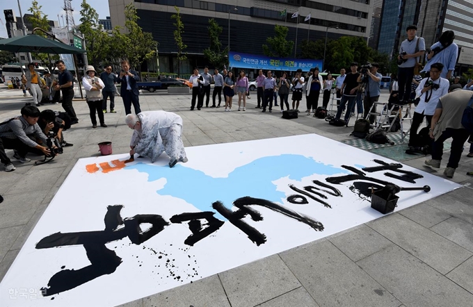 여태명 원광대학교 미술대학 교수가 제3차 평양 남북정상회담을 하루 앞둔 17일 오후 서울 광화문광장 세종대왕상 앞에서 '남북을 잇다, 통일을 열다' 대형 붓글씨를 쓰고 있다. 서재훈 기자