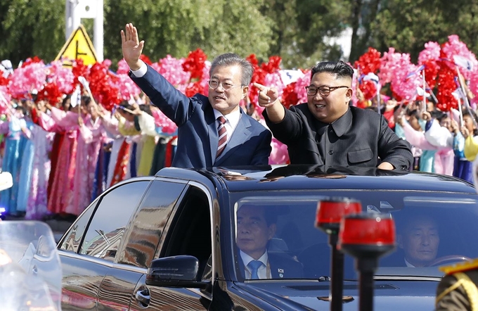 문재인 대통령과 북한 김정은 국무위원장이 18일 함께 무개차를 타고 평양국제공항에서 백화원 초대소로 향하며 평양 시민들을 향해 인사하고 있다. 연합뉴스