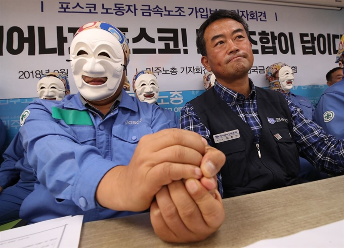 13일 오전 서울 중구 전국민주노동조합총연맹에서 포스코 노동자들이 연 전국금속노동조합 가입보고 기자회견에서 한 포스코 노동자가 김호규 금속노조 위원장의 손을 꼭 잡고 있다. 연합뉴스