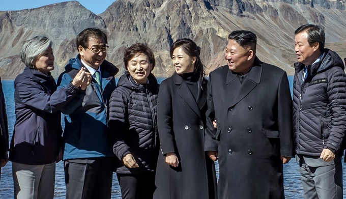 북한 김정은 국무위원장과 리설주 여사가 20일 백두산 천지에서 남쪽 수행원들과 기념사진을 찍던 중 강경화 외교부 장관으로부터 "남쪽에서 유행하는 손가락 하트를 해보자"는 제안을 받고 있다. 청와대 제공